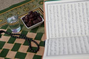 iftar time dátiles secos, vaso de agua del sagrado corán y tasbih en la alfombra de oración sarajevo foto