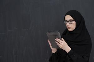 Young Arab businesswoman in traditional clothes or abaya holding tablet computer photo