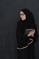 Young Arab businesswoman in traditional clothes or abaya holding tablet computer photo