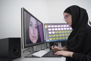 diseñadora gráfica musulmana que trabaja en una computadora usando una tableta gráfica y dos monitores foto
