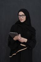 joven empresaria árabe con ropa tradicional o abaya sosteniendo una tableta foto