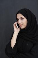 joven mujer de negocios musulmana con ropa tradicional o abaya hablando por teléfono inteligente foto