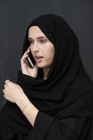 Young muslim businesswoman in traditional clothes or abaya talking on the smartphone photo