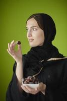 Young muslim girl wearing traditional muslim clothes holding dried dates