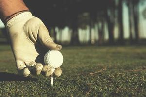 primer plano de la mano de los jugadores de golf colocando la bola en el tee foto