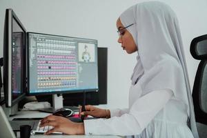 joven mujer de negocios musulmana moderna afroamericana que usa una bufanda en un lugar de trabajo creativo y brillante con una pantalla grande. foto
