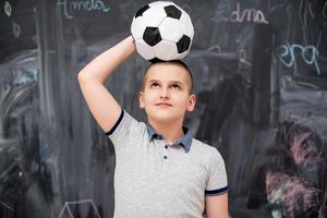 niño feliz sosteniendo un balón de fútbol en la cabeza foto