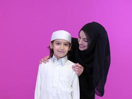 portrait of muslim mother and son on pink background photo