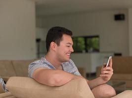 joven usando un teléfono móvil en casa foto