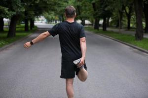 corredor masculino calentando y estirando antes del entrenamiento matutino foto