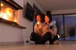 happy multiethnic couple sitting in front of fireplace photo