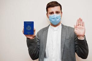 European man in formal wear and face mask, show San Marino passport with stop sign hand. Coronavirus lockdown in Europe country concept. photo