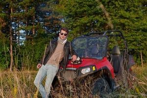 man enjoying beautiful sunny day smoking a cigarette while taking a break from driving a off road buggy car photo