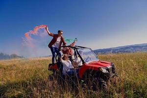 excited people having fun enjoying beautiful sunny day holding colorful torches while driving a off road buggy car photo