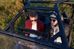 two young happy excited men enjoying beautiful sunny day while driving a off road buggy car photo