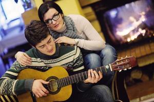 Young romantic couple sitting on sofa in front of fireplace at home photo