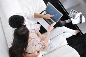 una pareja alegre se relaja y trabaja en una computadora portátil en una casa moderna foto