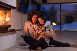 happy multiethnic couple sitting in front of fireplace photo