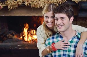 Young romantic couple sitting and relaxing in front of fireplace at home photo