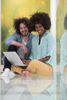 multiethnic couple using a laptop on the floor photo