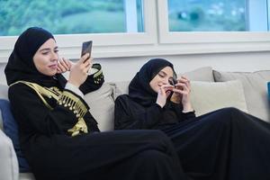 Portrait of Arabian girls wearing modern abaya using mobile phone photo