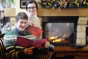 Young romantic couple sitting and relaxing in front of fireplace at home photo