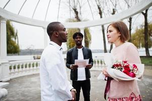 Wedding engagement ceremony with pastor. Happy multiethnic couple in love story. Relationships of african man and white european woman. photo