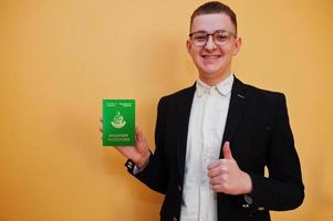 Young handsome man holding Republic of Vanuatu passport id over yellow background, happy and show thumb up.  Travel to Oceania country concept. photo