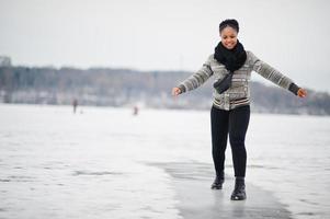 African woman wear in black scarf pose in frozen ice lake, winter day at Europe. photo