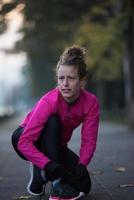 mujer estirándose antes de trotar por la mañana foto