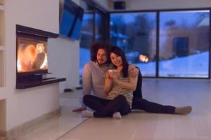 happy multiethnic couple sitting in front of fireplace photo