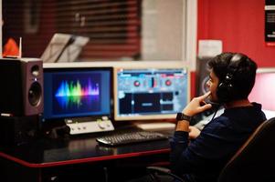 joven cantante asiático con micrófono grabando una canción en un estudio de música con productor de sonido. foto