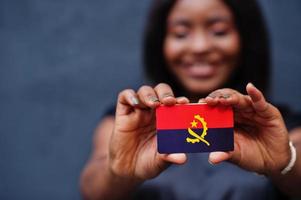 African woman hold small Angola flag in hands. photo