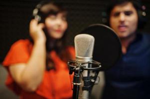 Young asian duet singers with microphone recording song in record music studio. photo