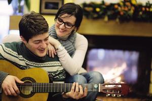 Young romantic couple sitting on sofa in front of fireplace at home photo