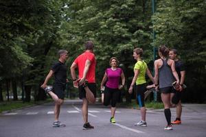 equipo de corredores calentando y estirando antes del entrenamiento matutino foto