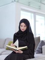 young muslim woman reading Quran at home photo