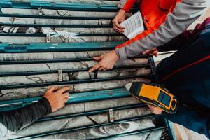 Geological gold core samples with team of mining workers measuring drilled rock top view. Selective focus photo