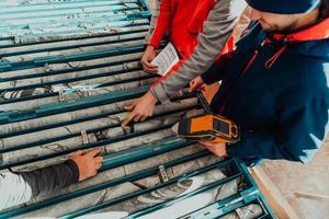 Geological gold core samples with team of mining workers measuring drilled rock top view. Selective focus photo