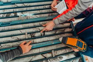 Geological gold core samples with team of mining workers measuring drilled rock top view. Selective focus photo