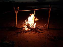 The bonfire burns in the evening on the shore of the lake photo