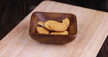 throwing a thin cookie falls from a plate on a wooden table photo