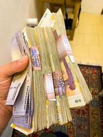 Hand hold iranian money banknotes after exchange 100 dollars photo