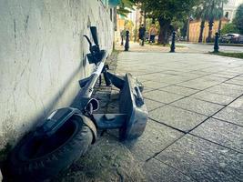 Batumi, Georgia , 2022 - electric public scooter in street broken damaged in public lay on ground. Safety and damage property photo