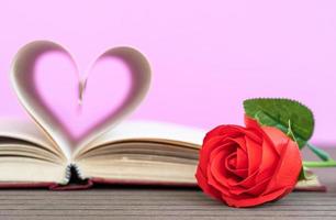 página del libro con forma de corazón curvo y rosa roja foto