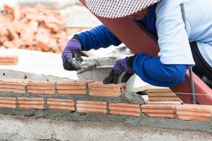 albañil trabajando en la construcción de una pared de ladrillos foto