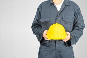 Close up Worker standing in blue coverall holding hardhat photo