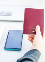 Primer plano de la mano de las mujeres que sostienen el pasaporte con la pantalla de espacio en blanco del teléfono inteligente foto