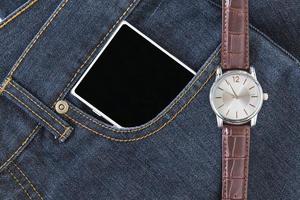 reloj de pulsera y teléfono inteligente en jeans foto