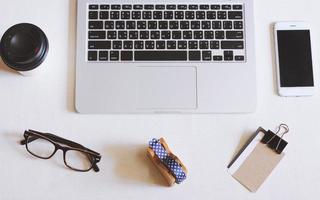 Flat lay photo of workspace desk with laptop, smartphone, eyeglasses and name card with copy space background